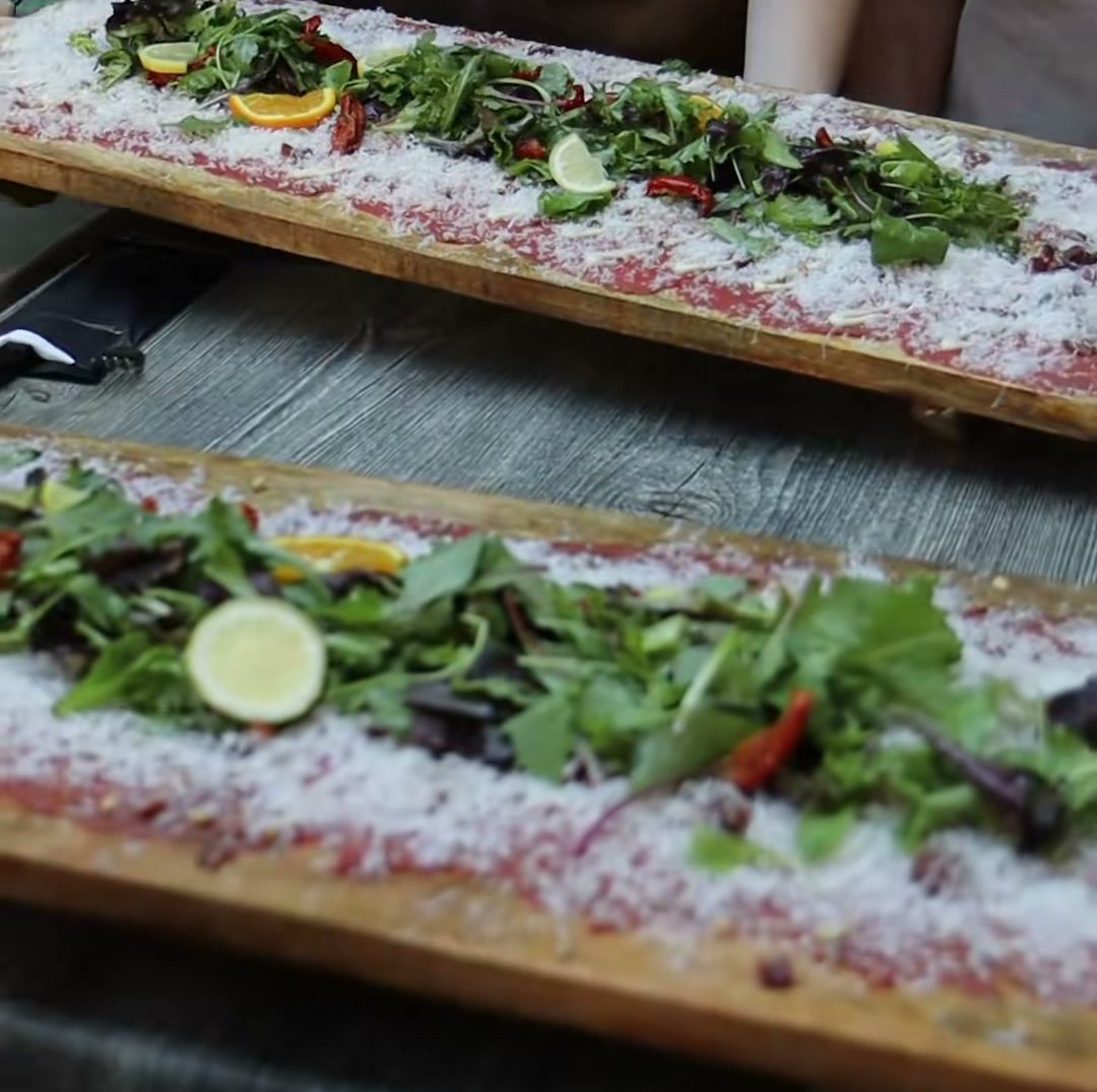 Planken meter carpaccio naast elkaar op één lange tafel